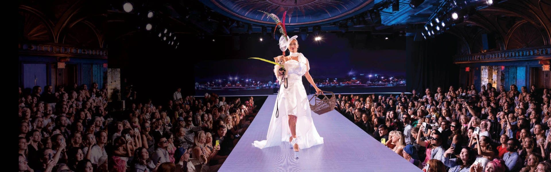 A model and her canine companion walk the Sony Hall runway, surrounded by the CatWalk FurBaby audience.